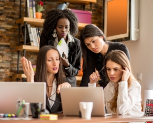 Image of a group of business women looking at a computer in collaboration